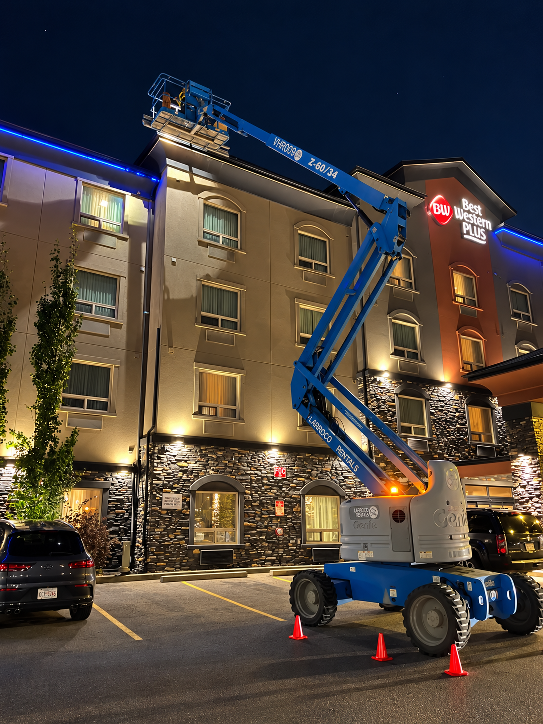 Boom lift in use at a hotel roofline at night