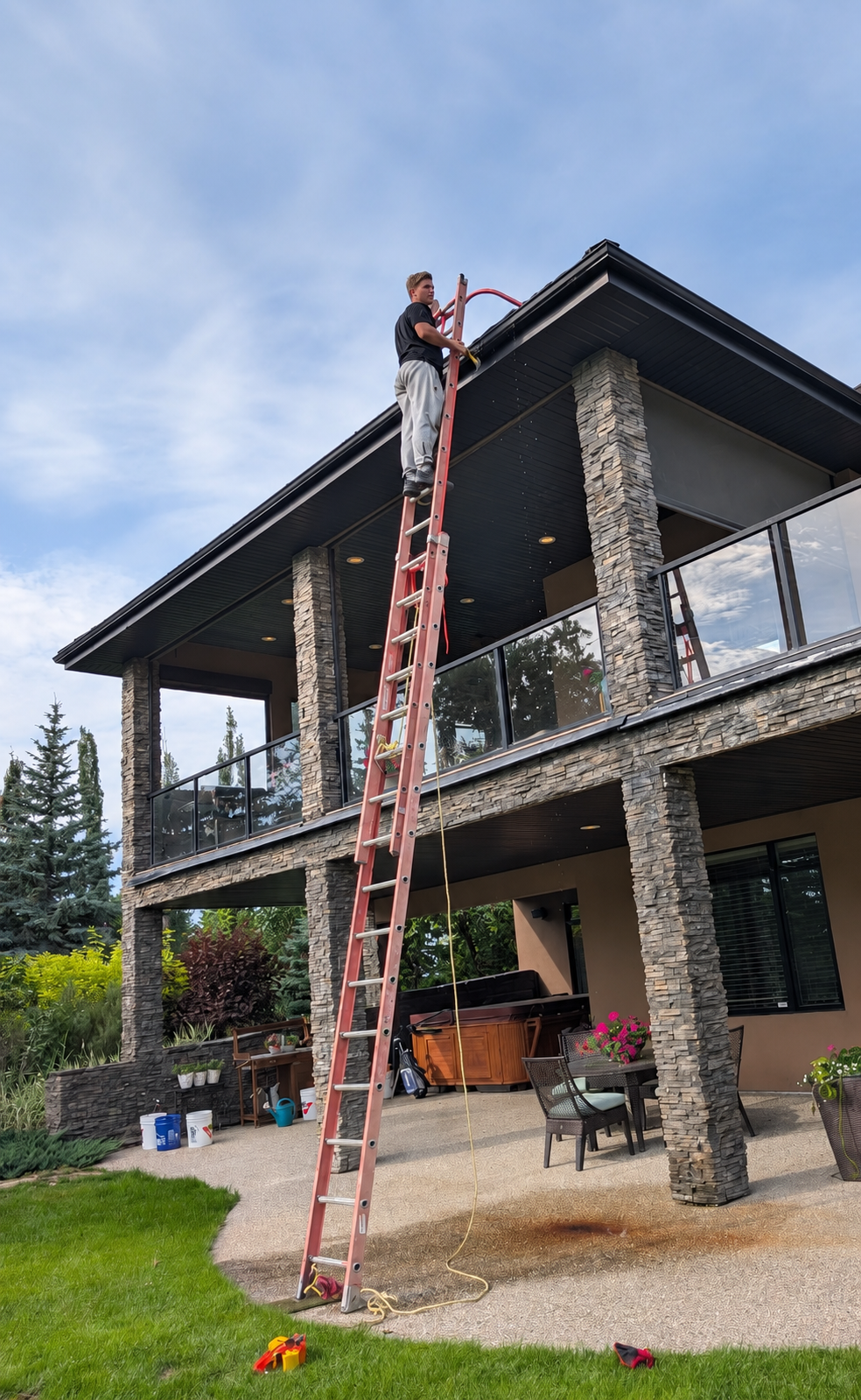 Re-Gutter technician working on the gutters of a stone-clad Edmonton home